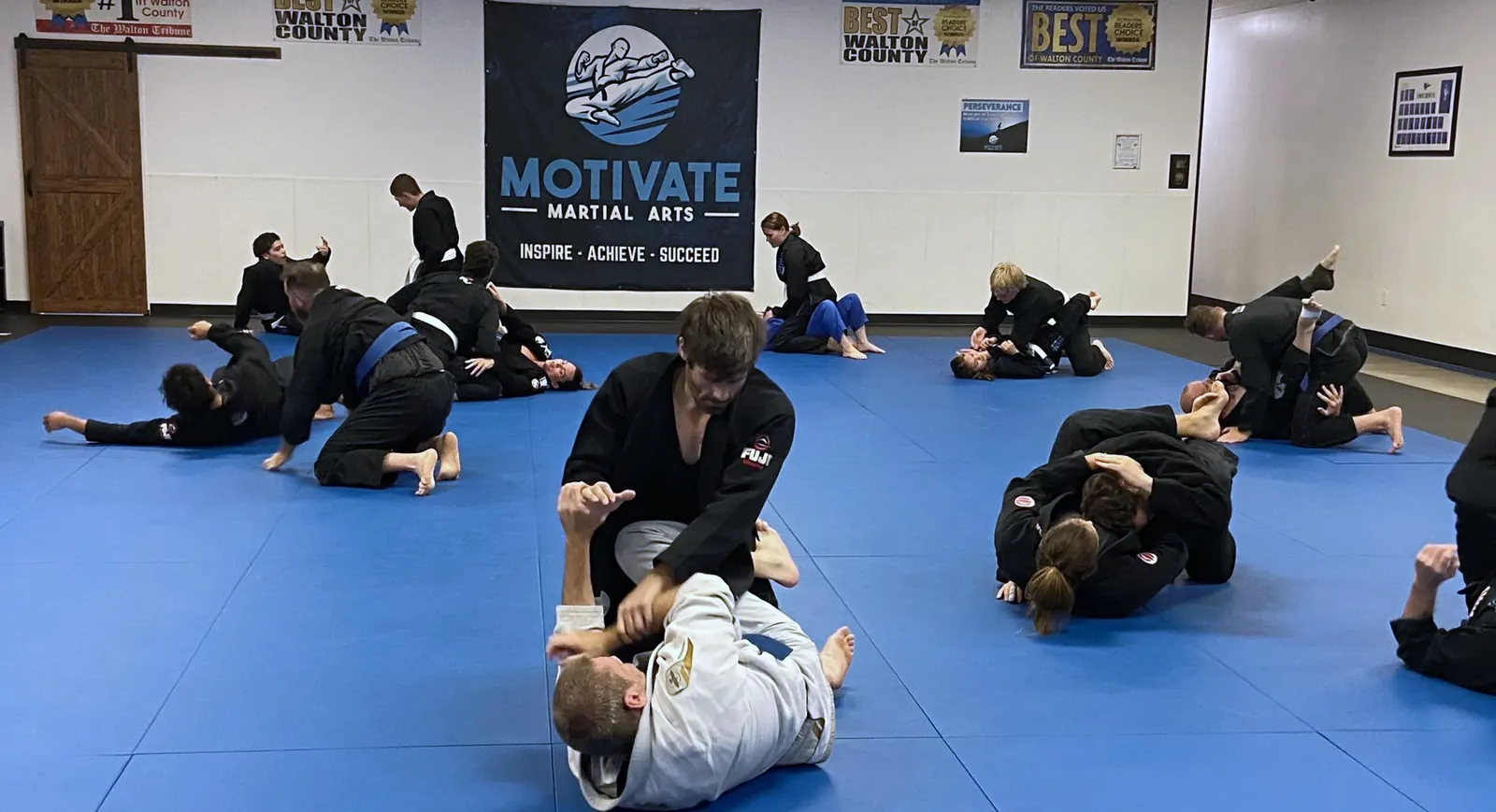 An Adult BJJ class training in gis on the blue mats