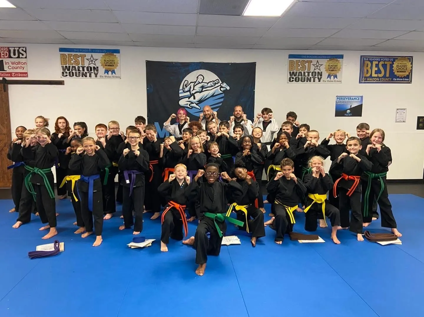 Motivate students celebrating new belts on the blue mats